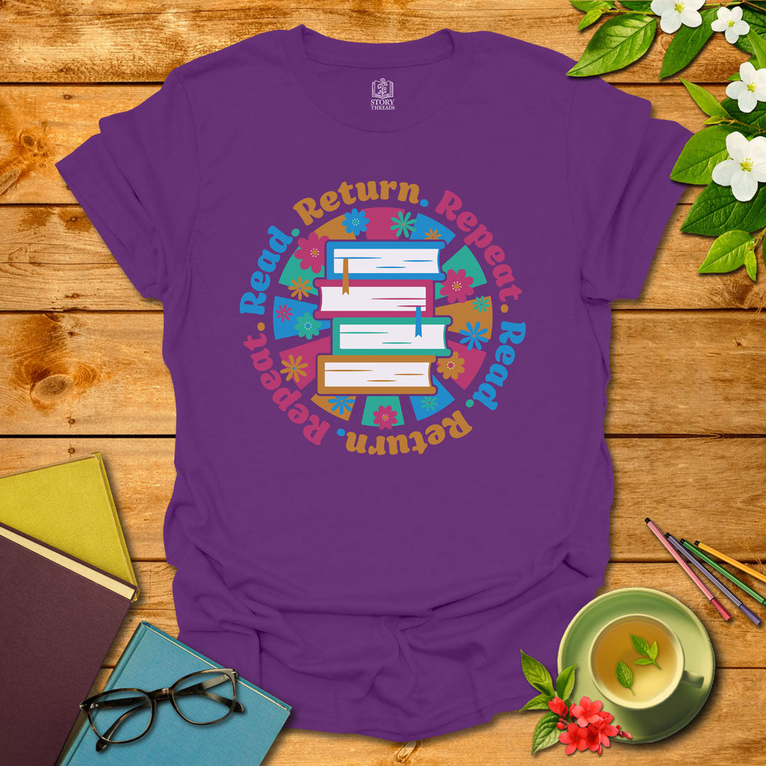 Purple unisex T-shirt with a colorful book stack and floral design, encircled by the phrase 'Read. Return. Repeat.' Displayed on a styled background with books and a cup of tea.